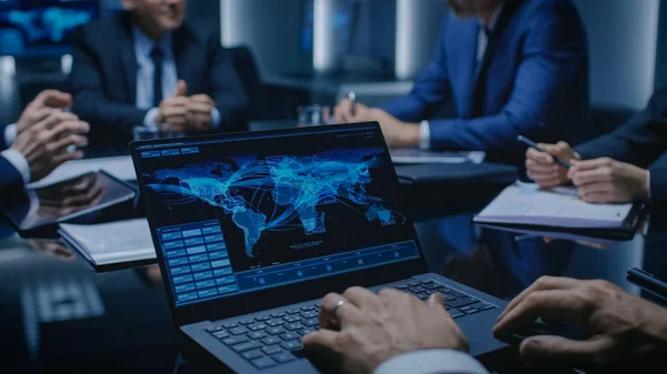 Auf dem Tisch Laptop mit weltweitem Datenfluss: Team aus Politikern, Unternehmensführern und Anwälten sitzt am Verhandlungstisch im Konferenzraum und versucht, zu einer Einigung zu kommen. — Stockfoto