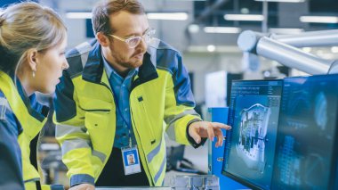 Fabrikada Erkek Makine Mühendisi ve Kadın Mühendis Kişisel Bilgisayarda Birlikte Çalışıyor, Robotik Kollar İçin 3D Motor Modelinin Detaylarını Tartışıyorlar..