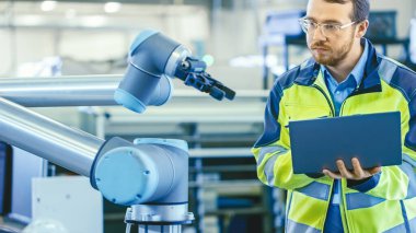 Fabrikada: Otomasyon Mühendisi Robotik Kol Programı için Dizüstü bilgisayar kullanıyor. Otomatik Üretim Endüstrisinde Yeni Dönem.