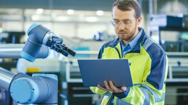 Fabrikada: Otomasyon Mühendisi Robotik Kol Programı için Dizüstü bilgisayar kullanıyor. Otomatik Üretim Endüstrisinde Yeni Dönem.