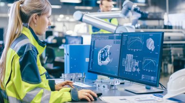 Fabrikada: Kadın Makine Mühendisi Kişisel Bilgisayarında 3D Motor Tasarımı Yaptı, Erkek Otomasyon Mühendisi Robotik Kolu Programlamak için Dizüstü Bilgisayarı Kullandı.