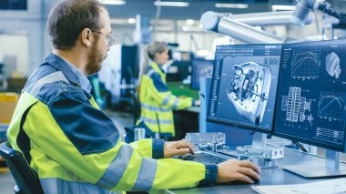 Fabrikada: Makine Mühendisi Bilgisayar 'da çalışıyor, CAD 3 boyutlu motor modeli tasarlıyor. Arkaplan Fabrikası İşçi ve Üretim Sürecinde.