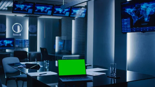 Foto van de System Control Monitoring Room. Een leeg operatiecentrum van de overheid. Op de tafel Laptop toont groen Mock-up scherm. — Stockfoto