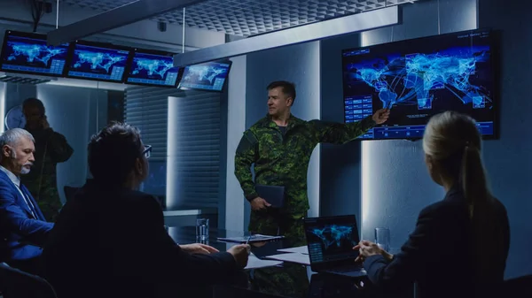 High-Ranking Military Man holder en briefing til et team af regeringsagenter og politikere, viser satellitovervågning optagelser. - Stock-foto