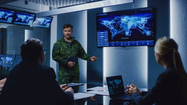 High-Ranking Military Man holder en briefing til et team af regeringsagenter og politikere, viser satellitovervågning optagelser. - Stock-foto