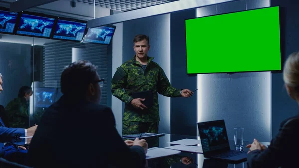 Militar de alto rango lleva a cabo una reunión informativa a un equipo de agentes gubernamentales y políticos, apunta a la pantalla verde Mock-up Wall TV. —  Fotos de Stock