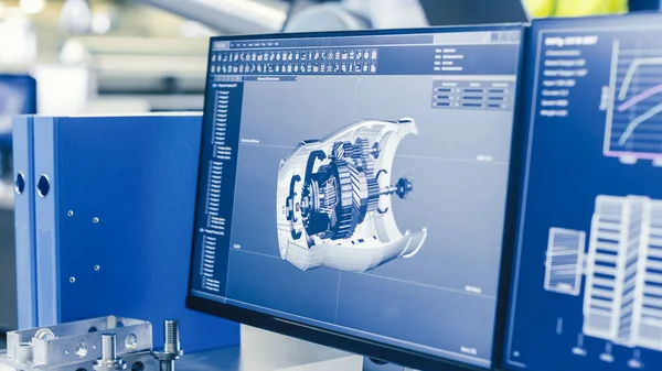 Close-up Opname van het 3D CAD-model van de motor weergegeven op het computerscherm. In de achtergrond Fabriek met mensen die werken. — Stockfoto