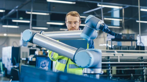 In fabbrica: l'ingegnere dell'automazione utilizza il computer portatile per la programmazione del braccio robotico. Nuova era nell'industria manifatturiera automatica. — Foto Stock