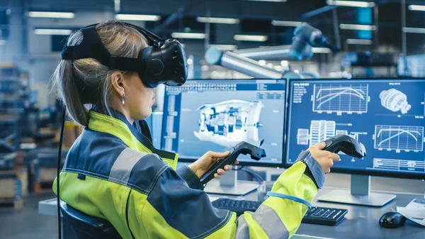工厂：女工业工程师头戴虚拟现实耳机，手持控制器，在CAD软件中使用VR技术进行工业设计、开发和原型设计. — 图库照片