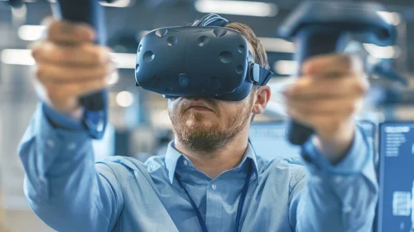Porträtt Skott av industriingenjören bär Virtual Reality Headset och Använda styrenheter, redo att arbeta. I bakgrunden tillverkningsanläggning och monitorer. — Stockfoto