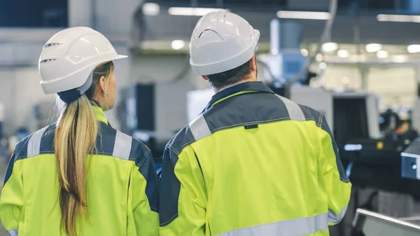 남성 산업 노동자 (Male Industrial Worker) 와 여성 수석 기계 공학자 (Female Chief Mechanical Engineer in Walk Through Manufacturing Plant), 토론 팩 토리 즈 뉴 프로젝트 (Discuss Factorys New Project). 시설에는 작업 기계가 있다. — 스톡 사진