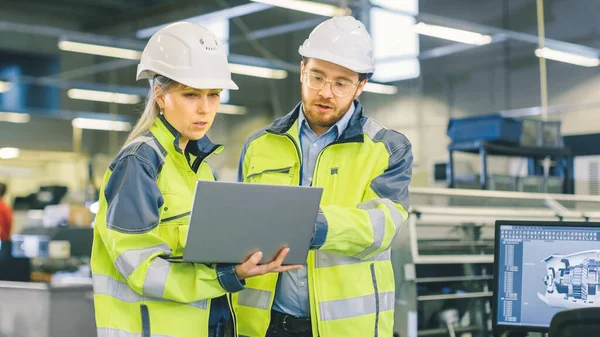 Trabajadora industrial masculina e ingeniera mecánica jefa en Walk Through Manufacturing Plant mientras discute el nuevo proyecto de Factorys y usa el portátil. Instalación tiene maquinaria de trabajo. — Foto de Stock