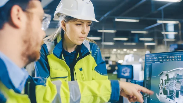 El ingeniero mecánico masculino de la fábrica y el ingeniero jefe femenino trabajan juntos en el ordenador personal, discuten detalles del diseño del modelo de motor 3D. — Foto de Stock