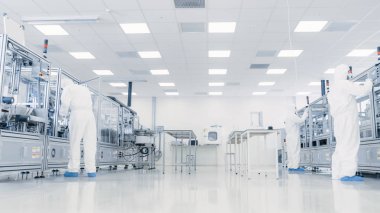 Steril Takım Elbiseli Araştırma Bilim Adamları Ekibi Laboratuvarda Bilgisayarlar, Mikroskoplar ve Modern Endüstriyel Makineler ile Çalışıyor. Ürün Üretim Süreci: İlaç, Yarı iletkenler