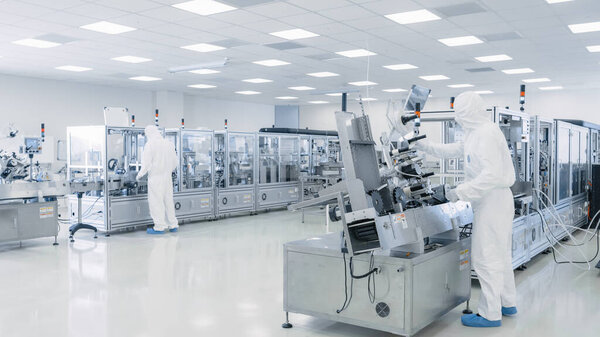 Sterile High Precision Manufacturing Laboratory where Scientists in Protective Coveralls Turn on Machninery, Use Computers and Microscopes, doing Pharmaceutics, Biotechnology and Semiconductor