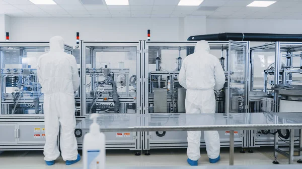 Fertigungslabor, in dem Wissenschaftler in Schutzanzügen mit industriellen Hochpräzisions-3D-Druckmaschinen arbeiten. Herstellung pharmazeutisch-technologischer Industrieprodukte. — Stockfoto