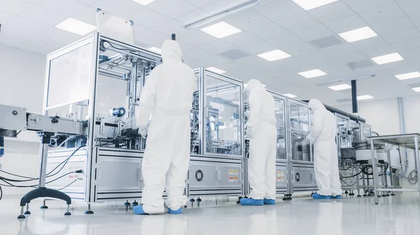 In der Produktionsanlage stellt das Team aus Wissenschaftlern, die sterile Schutzanzüge tragen, Programme für moderne industrielle 3D-Drucker auf, die hochpräzise Herstellung von Halbleitern im Prozess. — Stockfoto