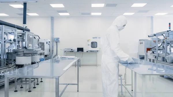 Científico en traje protector que trabaja con el caso del producto terminado a través del laboratorio. Trabajadores en las instalaciones con maquinaria industrial moderna. Proceso de fabricación de productos: Productos farmacéuticos — Foto de Stock