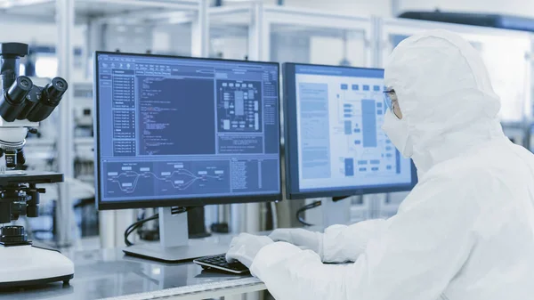 在实验室里，从科学家的肩部观点看防护服在个人电脑上做研究。现代手工生产半导体和药品. — 图库照片