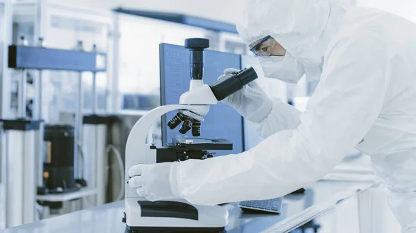 Em Laboratório Cientista em Roupas de Proteção Fazendo Pesquisa Usa Microscópio e Computador Pessoal. Fabricação moderna produzindo semicondutores e itens farmacêuticos. — Fotografia de Stock