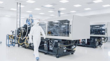 Steril Koruyucu Giysi Fabrikası 'nda çalışan bir bilim adamı Modern Endüstriyel 3D Baskı Makinesi üzerinde çalışıyor. İlaç, Biyoteknoloji ve Yarı iletken Üretim Süreci Oluşturma.