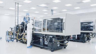 Steril Koruyucu Giysi Fabrikası 'nda çalışan bir bilim adamı Modern Endüstriyel 3D Baskı Makinesi üzerinde çalışıyor. İlaç, Biyoteknoloji ve Yarı iletken Üretim Süreci Oluşturma.
