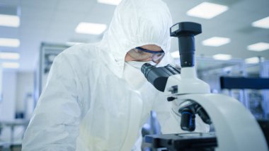 Koruyucu Giysiler Laboratuvarı 'nda mikroskop kullanarak araştırma yapıyor. Modern Manufactory Yarı iletkenler ve İlaç Ürünleri Üretimi.