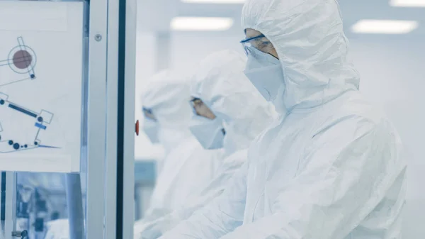 In un team di fabbrica di scienziati in indumenti protettivi sterili Lavorare su un moderno macchinario di stampa 3D industriale. Processo di produzione farmaceutico, biotecnologico e semiconduttore. — Foto Stock