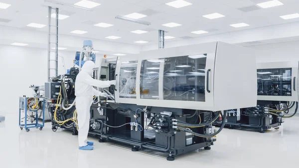 Über einen Fabrikwissenschaftler in steriler Schutzkleidung, der an einer modernen industriellen 3D-Druckmaschine arbeitet. Pharmazeutische, biotechnologische und Halbleiterfertigung. — Stockfoto