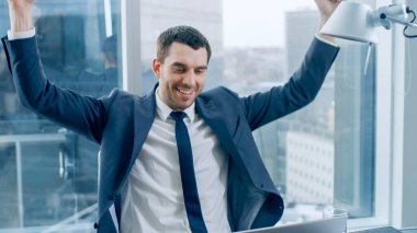 Başarılı İşadamı Masasında Otururken, Dizüstü bilgisayar üzerinde çalışırken, Büyük İş Kazanır ve Hedefe Ulaşmayı Kutlar, Kazanan Jest. Pencere Büyük Şehir İş Bölgesi Manzarasında.