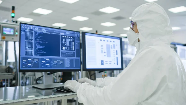 Shot of Scientists in Sterile Suits Working with Computers, Analyzing Data form Modern Industrial Machinery in Laboratory. Procédé de fabrication des produits : pharmaceutique, biotechnologie. Filtre jaune. — Photo
