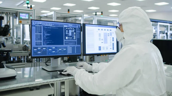 Lövöldözés egy steril öltönyös tudósokról, akik számítógépekkel dolgoznak, adatok elemzése modern ipari gépeket képeznek a laboratóriumban. Termékgyártási folyamat: Gyógyszeripar, félvezetők — Stock Fotó