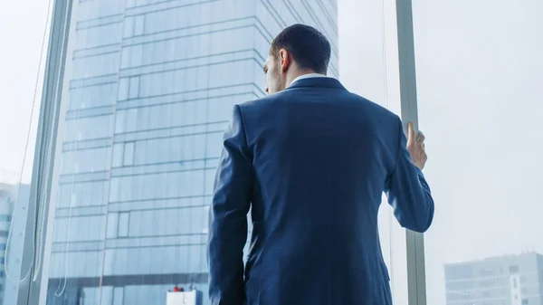 Low Angle Following Shot of the Confident Businessman in a Suit Standing in His Office and Looking out of the Window Thoughtfully. Stylish Modern Business Office with Big City View. — Stock Photo, Image