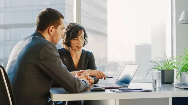 Female Top Manager and Male Businessman Sitting at the Desk Have Discussion and Working on the Laptop, Solving Problems Успішні люди в сучасному офісі з діловим районом Великого міста — стокове фото