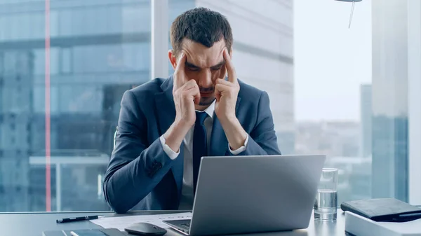 Stressed Out Businessman Sitting at His Desk, Massages His Head in Frustration. Trying to Concentrate. Overworked Businesspeople In the Window Big City Business District View. — Stock Photo, Image