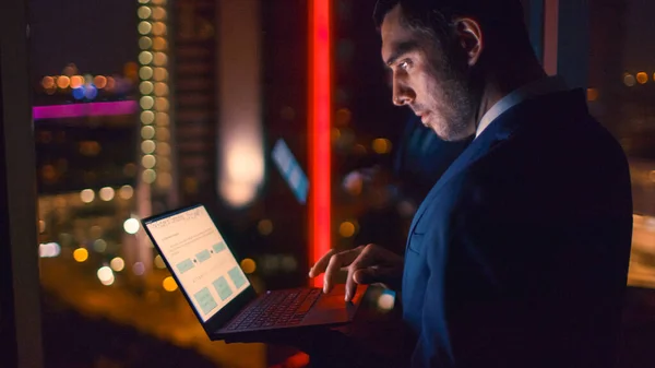 Tarde da noite no escritório Empresário bem sucedido detém laptop enquanto trabalhava nele. Na janela Business District View com luzes da cidade. — Fotografia de Stock