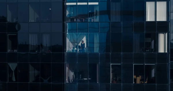 Vue aérienne de l'extérieur vers un immeuble de bureaux avec un homme d'affaires regardant par la fenêtre. Belle prise de vue des gratte-ciel du quartier financier. — Photo