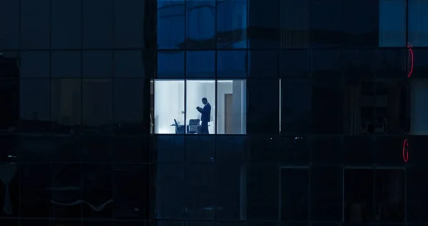 Légi felvétel: Kívülről irodaépületbe üzletemberrel mobiltelefont használva és az irodaablaknál állva. Gyönyörű lövés a Financial Business District felhőkarcolók. — Stock Fotó