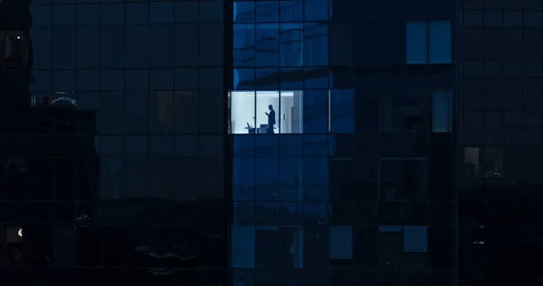 Légi felvétel: Kívülről irodaépületbe üzletemberrel mobiltelefont használva és az irodaablaknál állva. Gyönyörű lövés a Financial Business District felhőkarcolók. — Stock Fotó
