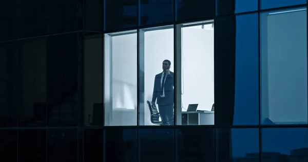 Luftaufnahme: Von draußen in das Bürogebäude mit Geschäftsmann, der sein Handy benutzt und am Bürofenster steht. Schöne Aufnahme der Wolkenkratzer des Financial Business District. — Stockfoto