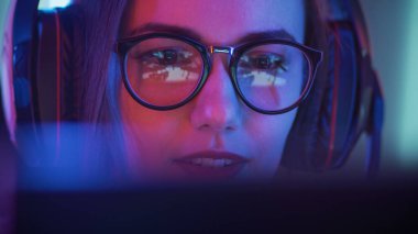 Güzel, profesyonel oyuncu kız video oyunu akışı yapıyor, gözlük takıyor. Arka planda Neon Retro Renkleriyle Çekici İnek Kız.