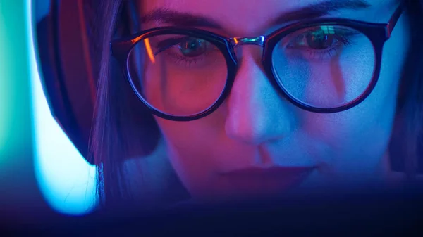 Portrét krásné mladé dívky sedí před počítačem, prohlížení na internetu, hraní online her, streaming. Roztomilé dívky s brýlemi v chladném Retro neon Lit Room. — Stock fotografie