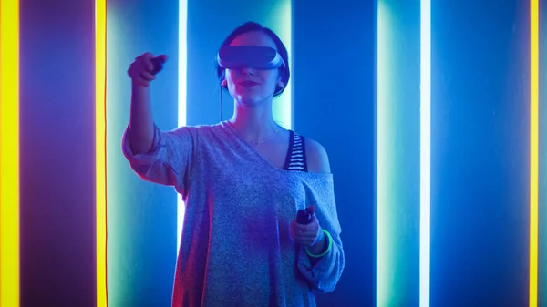 Beautiful Young Girl Wearing Virtual Reality Headset Using Joysticks Controllers. Creative Young Girl Does Concept Art with Augmented Reality. Playing Online Video Game. Neon Retro Lights Surround Her — Stock Photo, Image