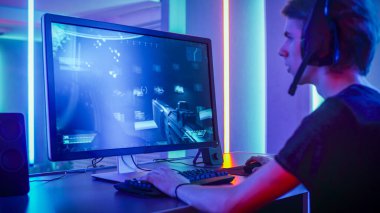 Shot of the Professional Gamer Playing in First-Person Shooter Online Video Game on His Personal Computer. Room Lit by Neon Lights in Retro Arcade Style. Online Cyber e-Sport Internet Championship. clipart