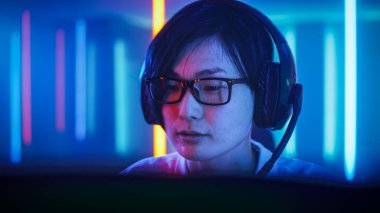 Profesyonel Doğu Asyalı Oyuncu, Kişisel Bilgisayarında Online Video Oyunu 'nda oynuyor. Takımıyla mikrofon aracılığıyla konuşuyor. Neon Lights 'ın Retro Arcade Style' daki oda aydınlatması. Siber Spor Şampiyonası.