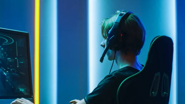 Pro Gamer juega en la primera persona Shooter en su ordenador personal. Habla con compañeros de equipo a través de auriculares. Habitación de color neón. Torneo de eSport en línea en acción. — Foto de Stock