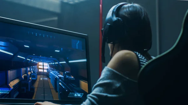 Vacker professionell Gamer Girl spelar i First-Person Shooter Online TV-spel på hennes personliga dator. Snygga, avslappnade nördflicka som bär headset. I Underground Gaming Club. — Stockfoto