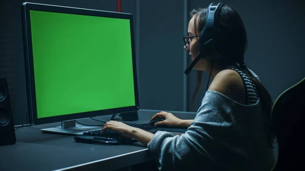 美しいプロゲーマーの女の子グリーンスクリーンモックアップテンプレートと彼女のパーソナルコンピュータ上のビデオゲームで再生します。カジュアルかわいいギークの女の子はヘッドセットを身に着けて.地下ゲームクラブで. — ストック写真
