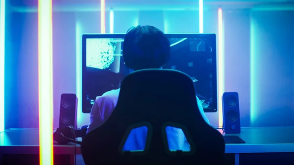 在他的个人电脑上玩第一人称射击在线视频游戏的职业游戏玩家的背景镜头。新灯饰风格的复古拱廊风格的房间。网上电子体育互联网 — 图库照片