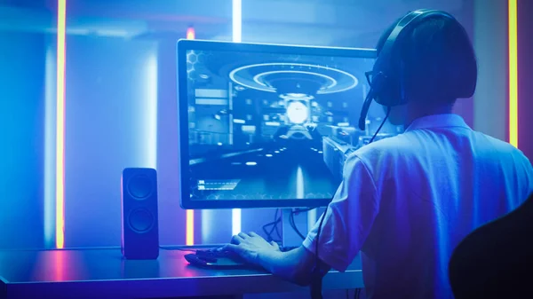 Arc Skott av den professionella Gamer spelar i First-Person Shooter Online TV-spel på sin personliga dator. Han pratar med sitt team genom headset. Rummet tänt av Neon Lights i Retro Arcade Style — Stockfoto